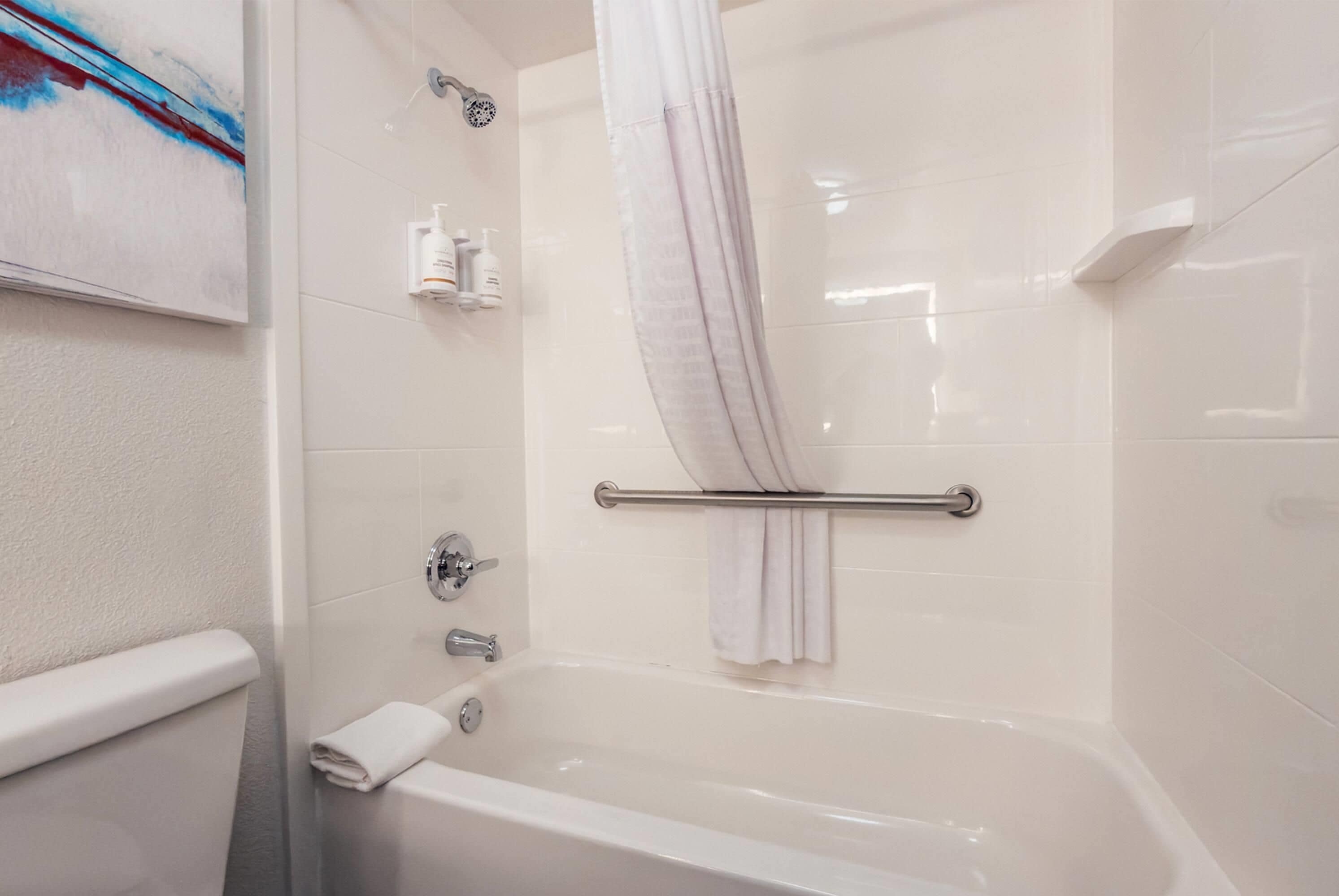 A modern bathroom with a bathtub, a shower curtain, and a towel rack.