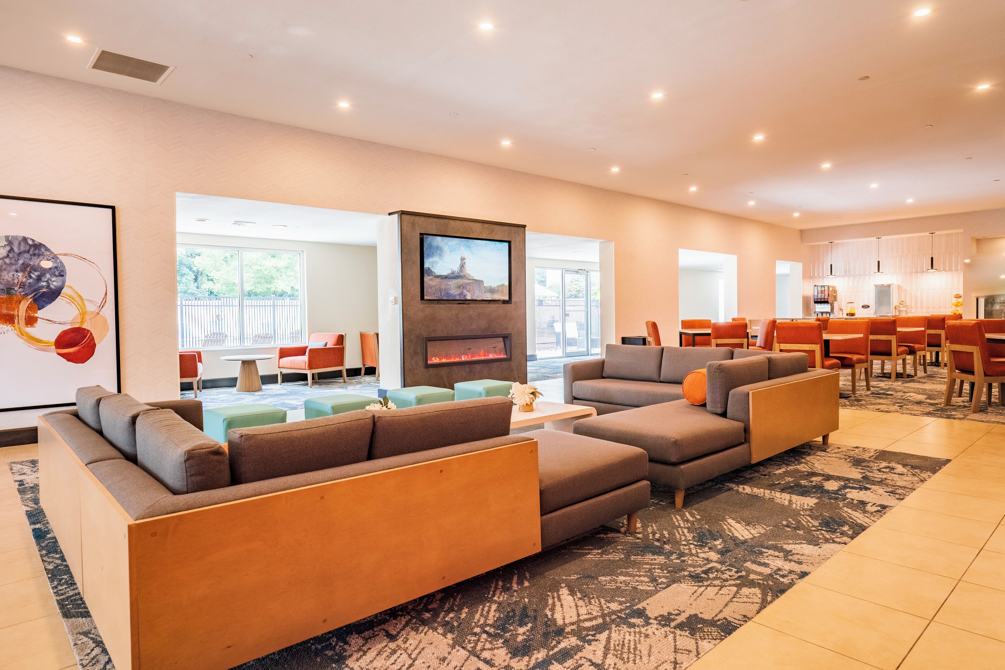 A spacious living area with a fireplace, comfortable seating, and a large window offering a view of the outdoors.