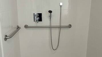 Un espacio de ducha con un cabezal de ducha de mano y un grifo empotrado.