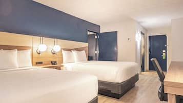Een hotelkamer met twee bedden, een bureau en een deur.
