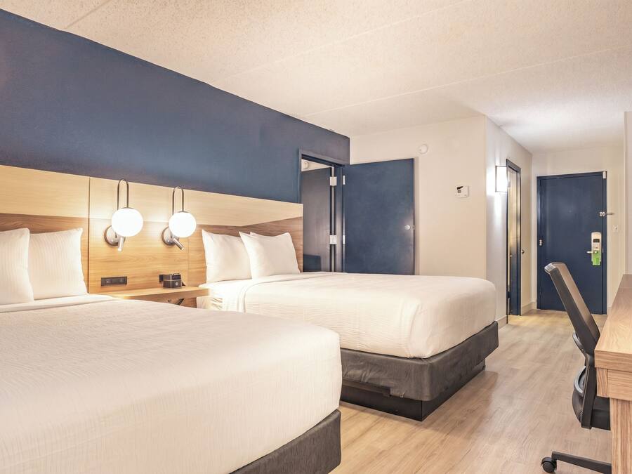 Een hotelkamer met twee bedden, een bureau en een deur.