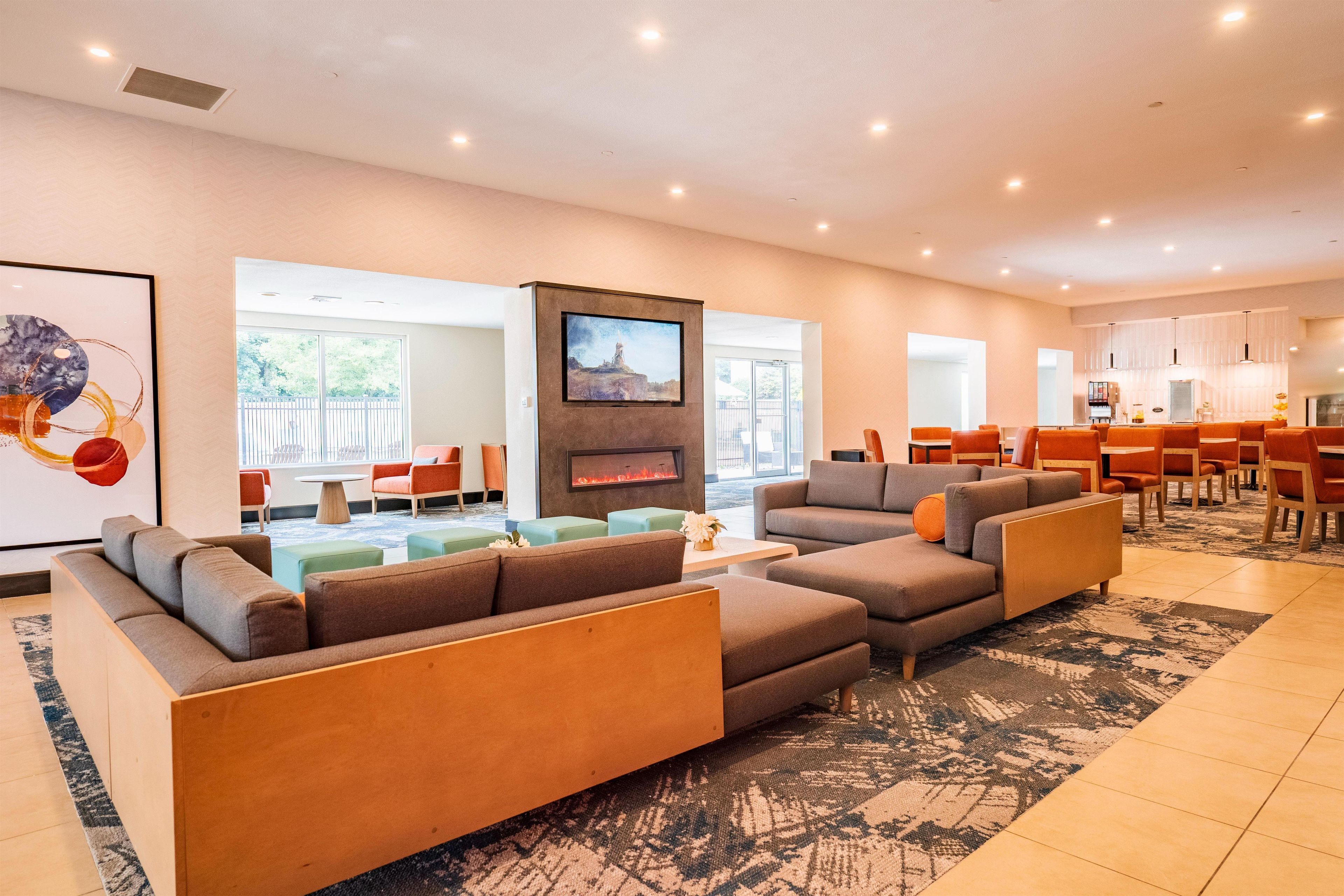 A modern living room with a fireplace, sofas, and a dining area.
