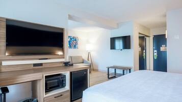 Une chambre d’hôtel moderne équipée d’un lit, d’une télévision, d’un four à micro-ondes et d’un bureau avec une chaise.