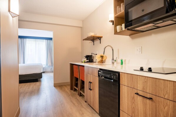 A compact hotel room with a kitchenette, a bed, and a view of the outdoors. - La Quinta Inn & Suites by Wyndham Danbury (Danbury)