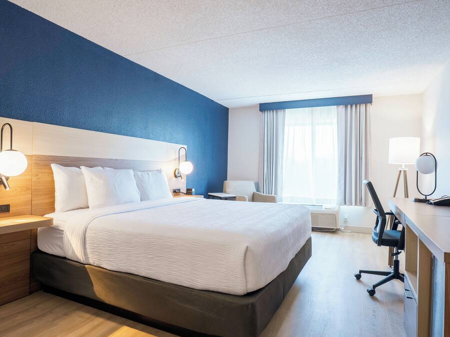 Una habitación de hotel con una cama grande, mesitas de noche, un escritorio y una silla.
