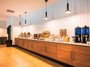 A breakfast buffet with various food items, coffee machines, and a modern kitchen design. - La Quinta Inn & Suites by Wyndham Danbury (Danbury)