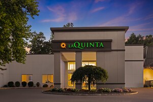 Un hotel llamado La Quinta con una fachada moderna, una entrada central y un jardín bien cuidado.