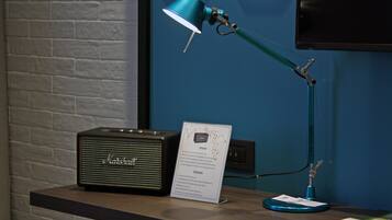 Un bureau agrémenté d’un amplificateur Marshall vintage, d’une lampe de bureau de couleur turquoise et d’un panneau indiquant les consignes.