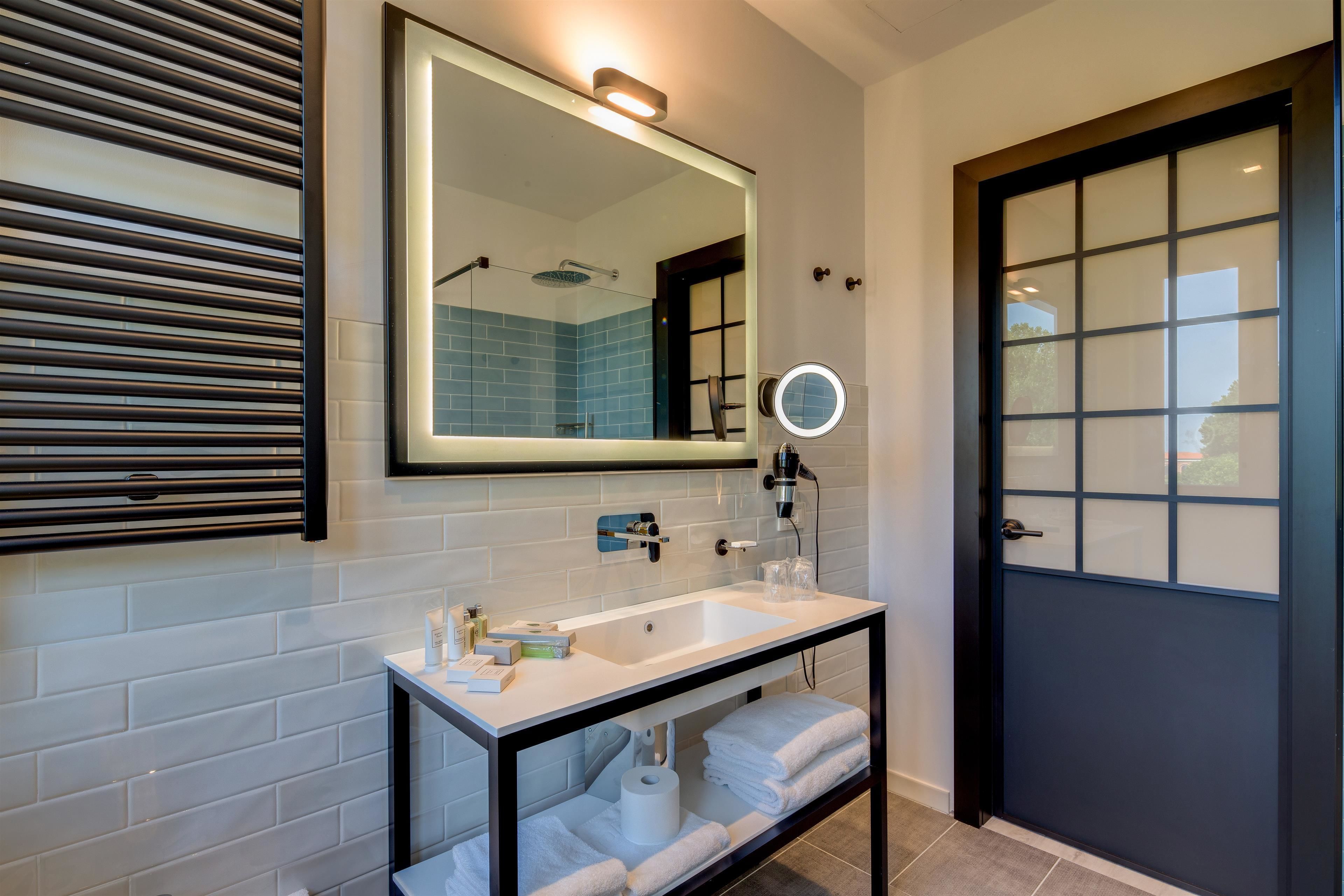 Un baño moderno con un lavamanos blanco, un espejo y un perchero para toallas.