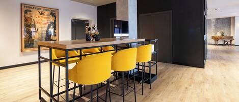 Un interior moderno con una zona de bar que presenta sillas amarillas, una mesa de madera y un cartel en la pared.