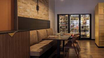 A modern restaurant with a brick wall, a wooden bench, a dining table with chairs, and a wine refrigerator.