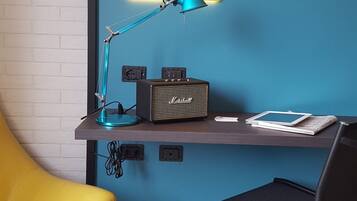 Un escritorio con una pared azul, una lámpara, un amplificador Marshall y una silla.