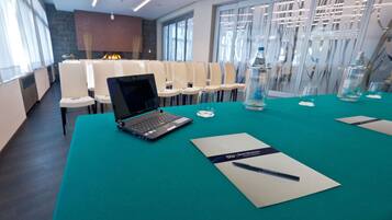 Una sala conferenze con un tavolo verde acqua, laptop e cartellini con i nomi.