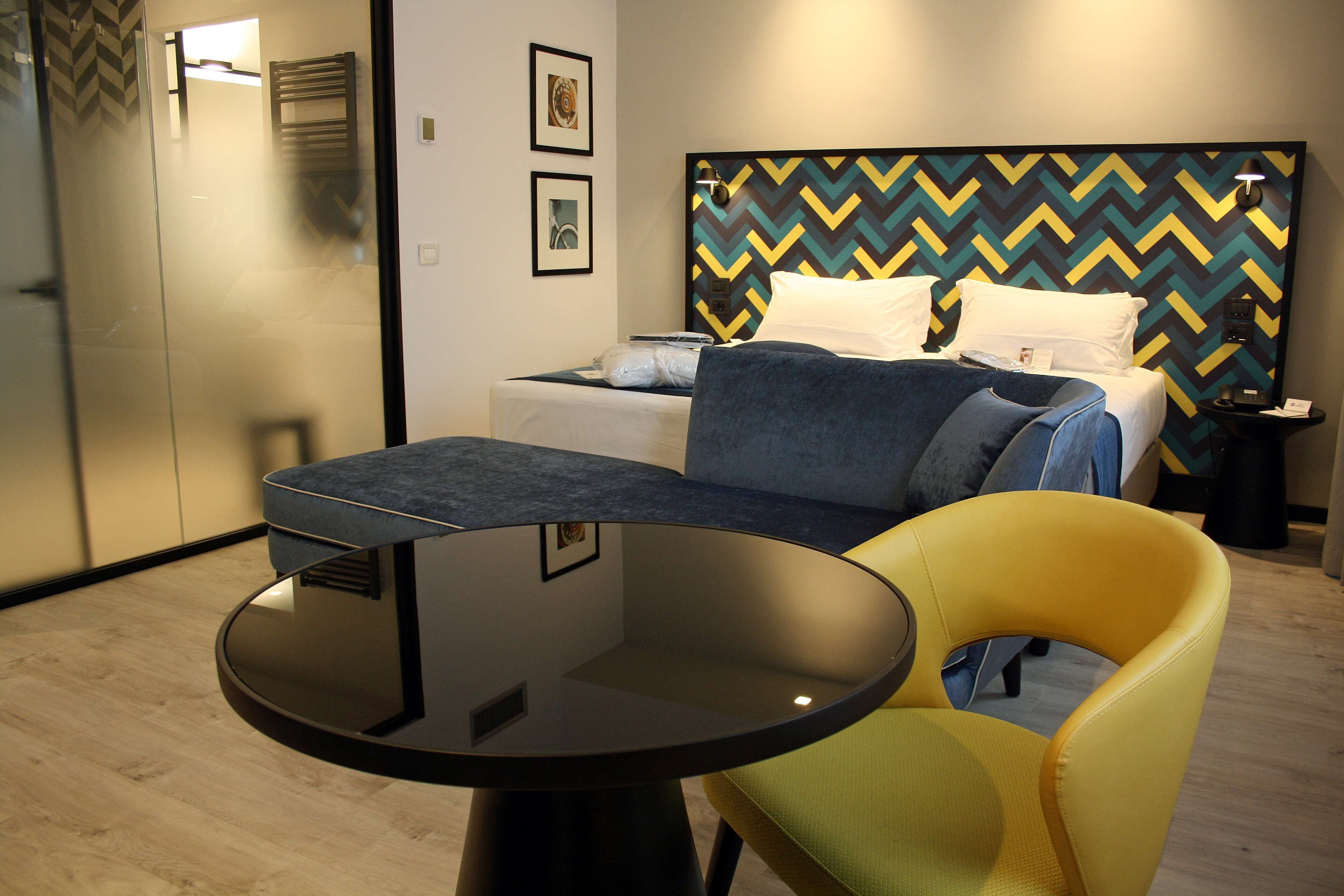 Ein modernes Hotelzimmer mit einem Bett, einem runden Tisch und einem gelben Sessel.