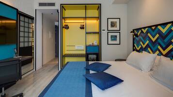 A hotel room with a bed, a desk, a chair, a wardrobe, and a mirror.