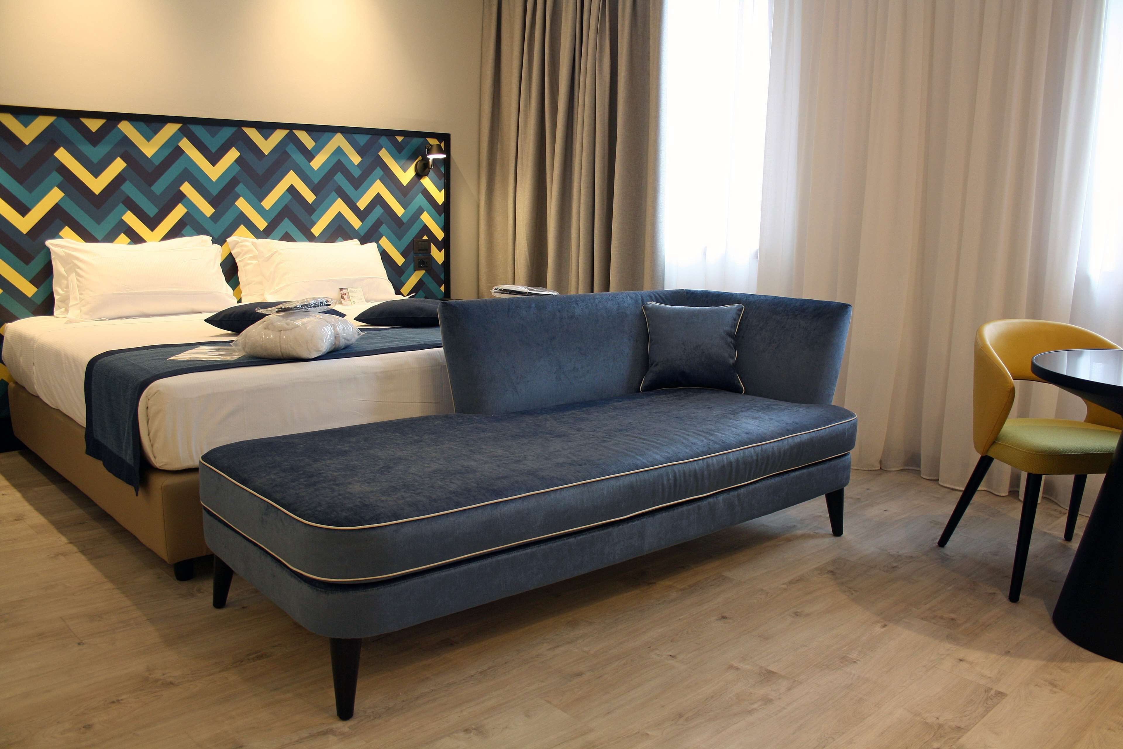 A hotel room with a bed, a sofa, a chair, and a table.
