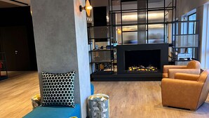 Ein modernes Wohnzimmer mit Kamin, blauem Sofa und orangenem Sessel.