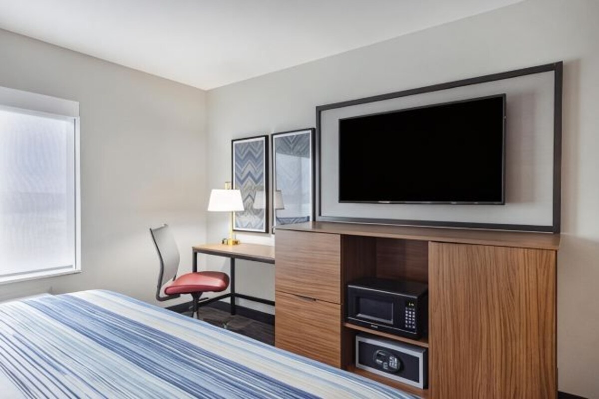 A hotel room with a bed, a desk with a chair, a television, and a microwave.