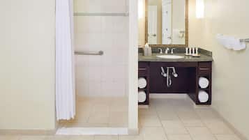 A bathroom with a shower, a sink, a mirror, and a towel rack.