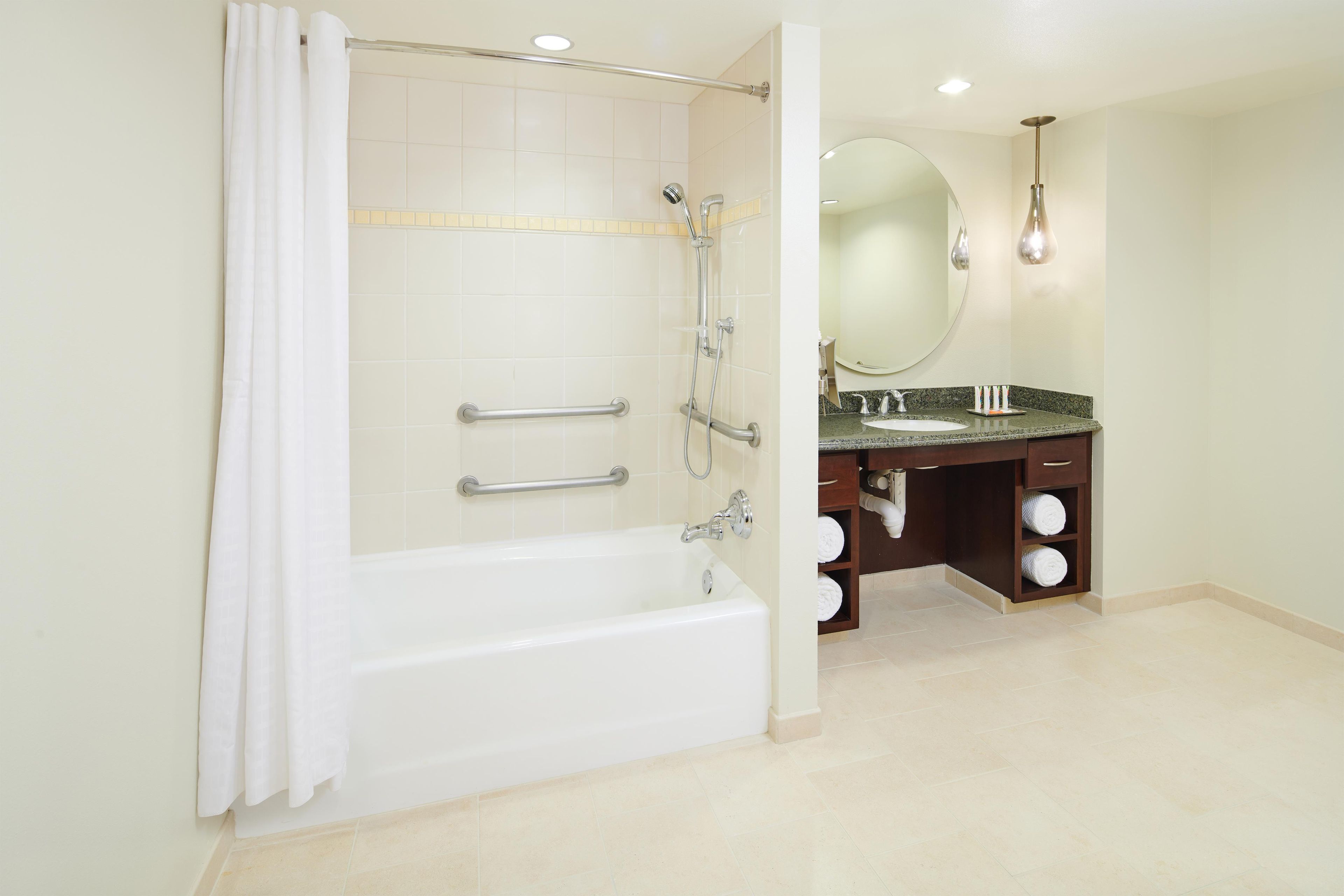 A modern bathroom with a bathtub, shower, and vanity with a mirror.