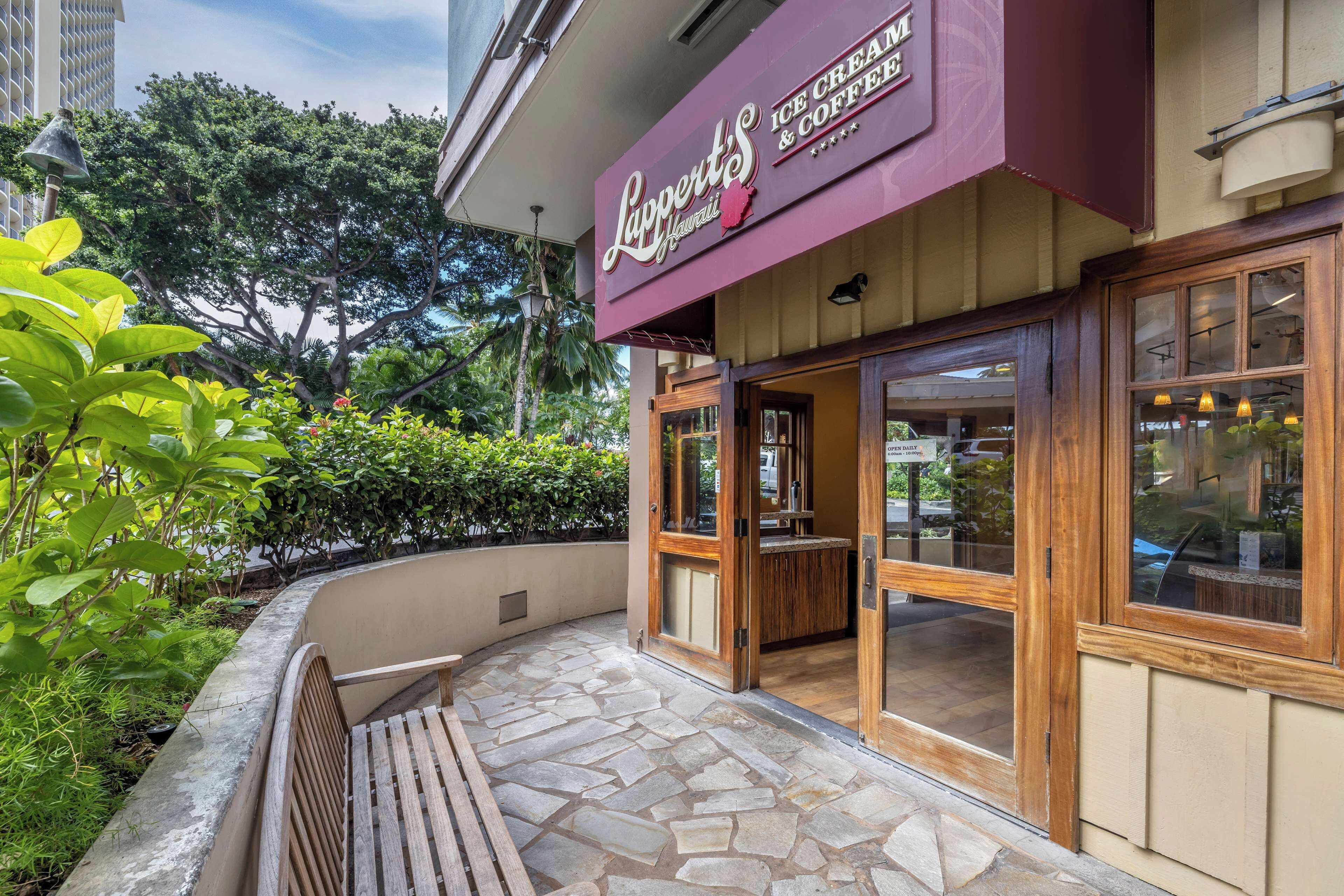 A restaurant with a stone-tiled entrance, wooden bench outside, and a signboard above the entrance.