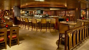 Un espace bar avec des tabourets de bar en bois, un comptoir et un écran de télévision.