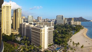 A coastal cityscape with high-rise buildings, a beach, and a pier with a boat. - Hilton Grand Vacations Club Grand Waikikian Honolulu (Honolulu)