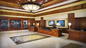 A spacious lobby with a large reception desk, wooden paneling, a chandelier, and artwork on the walls. - Hilton Grand Vacations Club Grand Waikikian Honolulu (Honolulu)