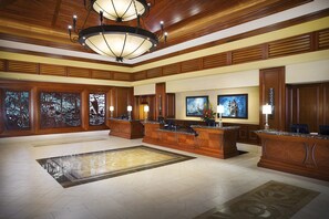 A spacious lobby with a large reception desk, wooden paneling, a chandelier, and artwork on the walls. - Hilton Grand Vacations Club Grand Waikikian Honolulu (Honolulu)