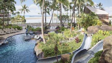 A resort pool with a water slide, lounge chairs, and palm trees.