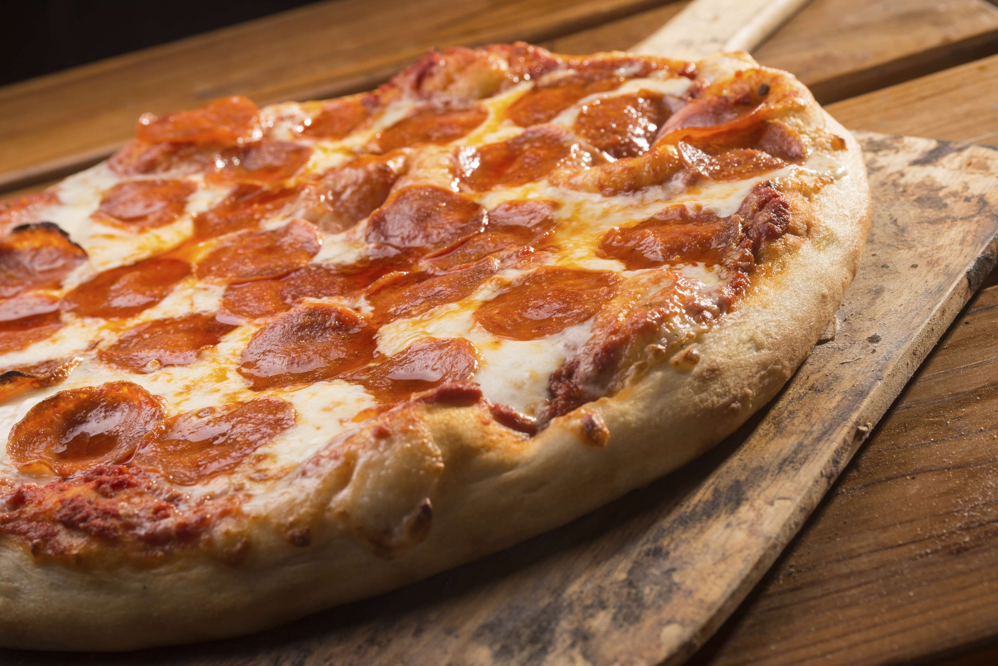 A pizza on a wooden cutting board.