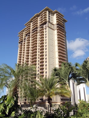 Ein hohes, mehrstöckiges Hotel mit Balkonen, umgeben von Palmen.