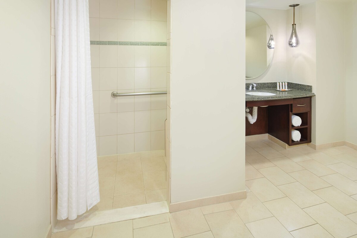 A bathroom with a shower, a sink, and a mirror.