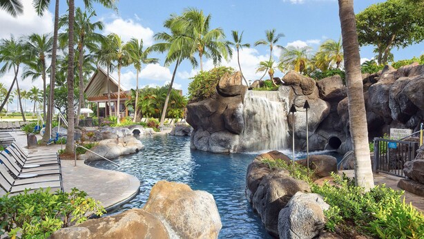 A pool area with a waterfall, palm trees, and lounge chairs. - Hilton Grand Vacations Club Grand Waikikian Honolulu (Honolulu)