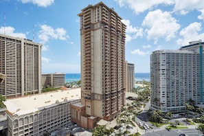 Un hotel moderno de gran altura con varios balcones, vista al mar y un estacionamiento.