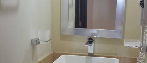 A bathroom with a white sink, a mirror, and a towel rack.