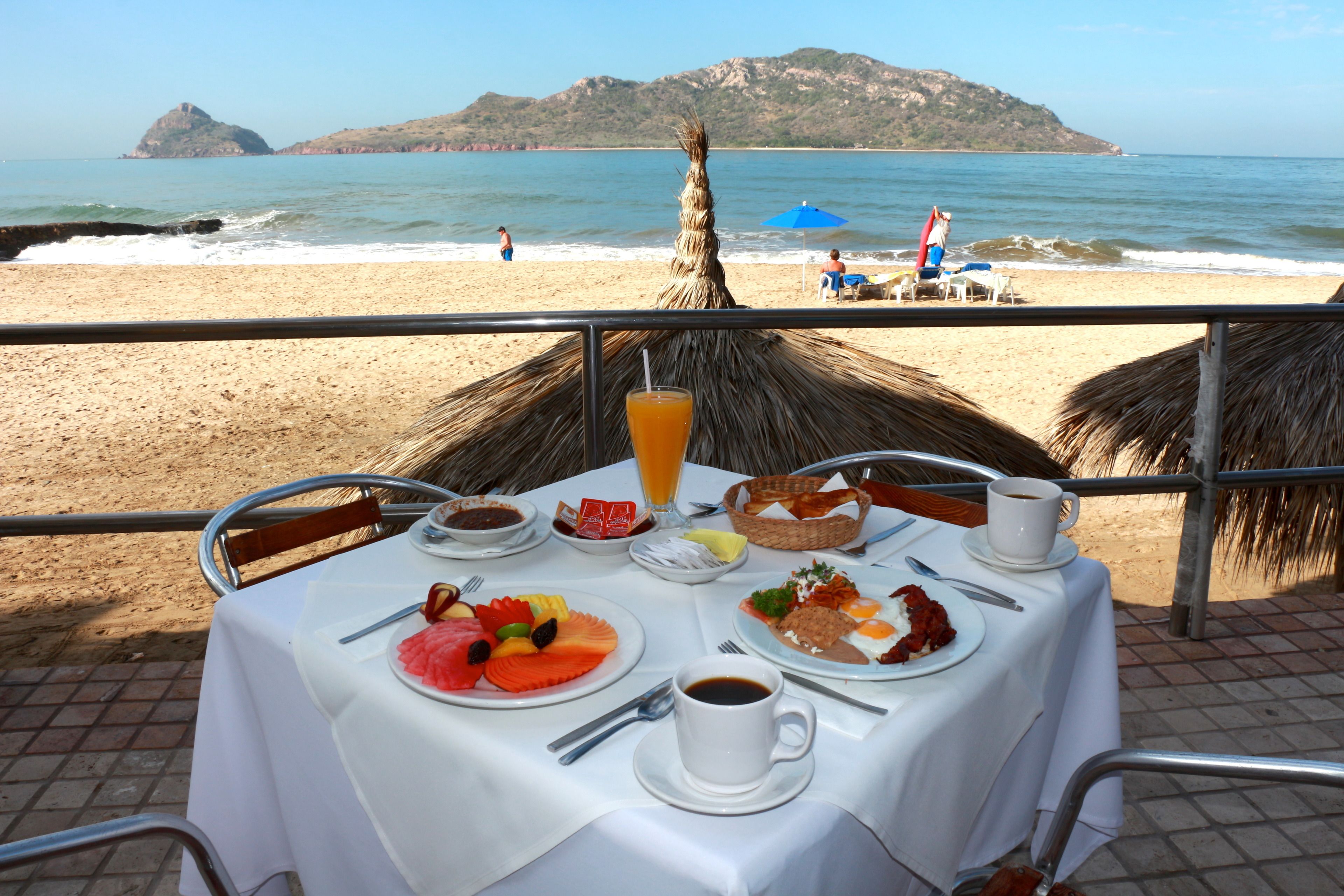 A table set for breakfast with a view of the beach and ocean.