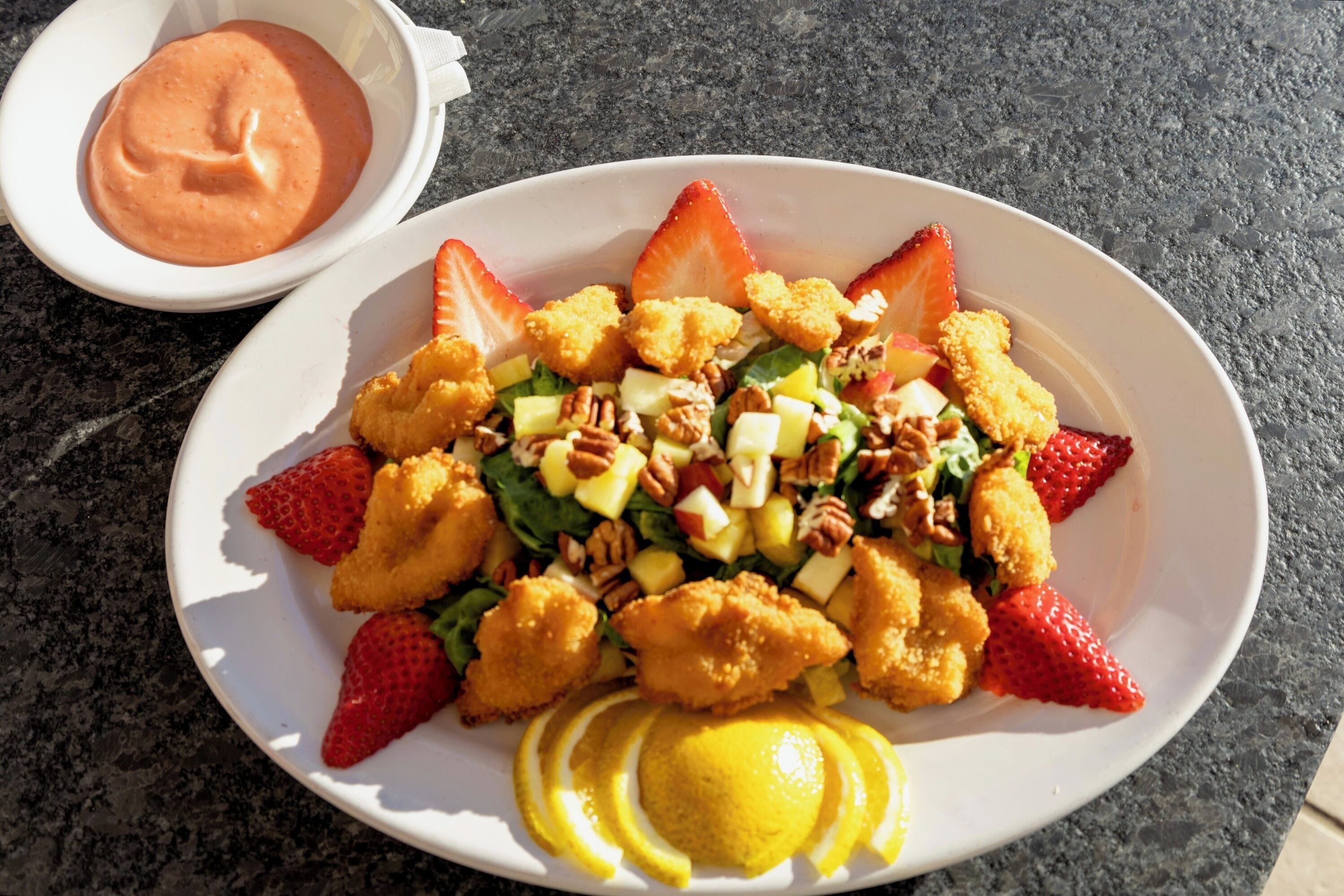 Un plato de comida con fresas, nueces y una salsa al lado.