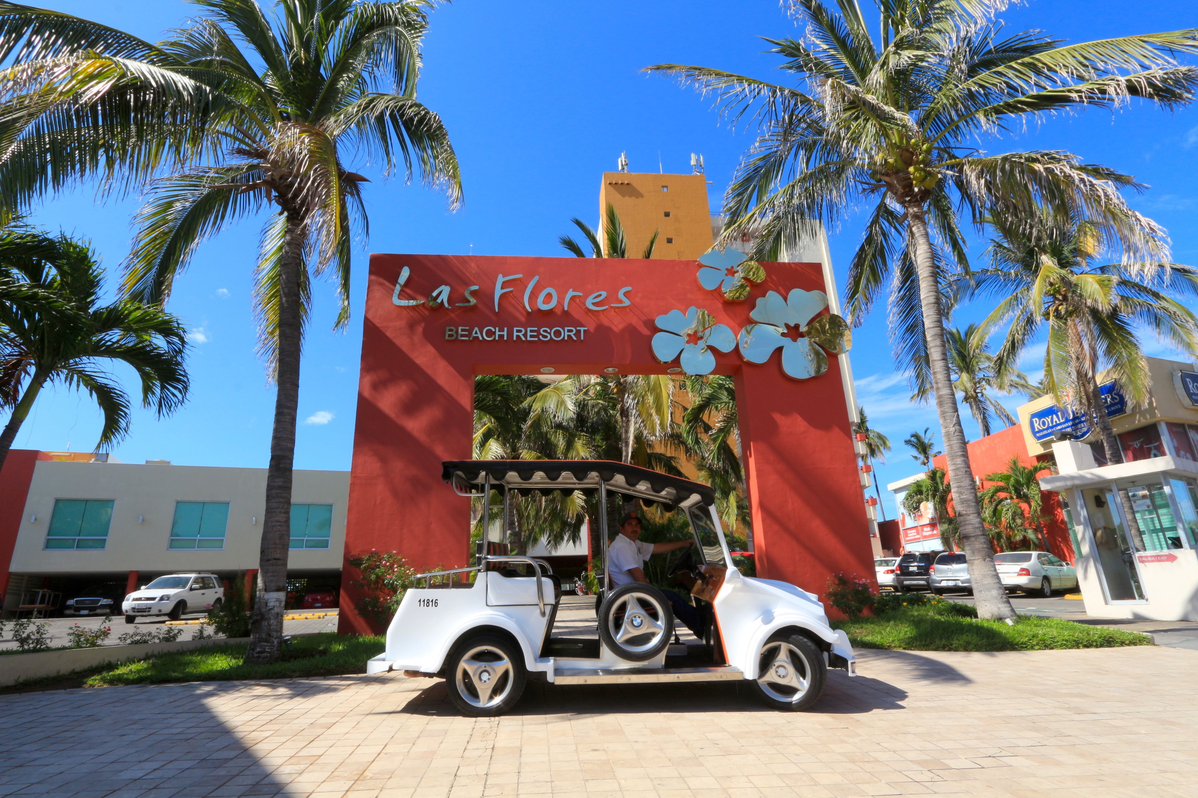 Un carrito de golf estacionado frente a un letrero de Las Flores Beach Resort.