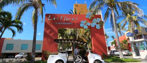 Un carrito de golf estacionado frente a un letrero de Las Flores Beach Resort.