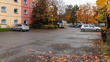 Un estacionamiento con coches, un edificio con un letrero que dice 'HOTELS' y hojas de otoño en el suelo.