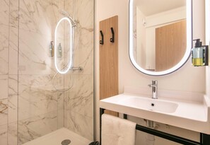 A modern bathroom with a glass-enclosed shower, a large mirror, and a white sink. - B&B Hotel Grenoble Université 2 (Gieres)