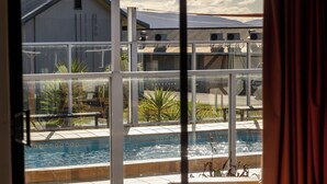 A hotel room with a large window overlooking a swimming pool and a building with a sloped roof. - Beachfront At Bicheno (Bicheno)