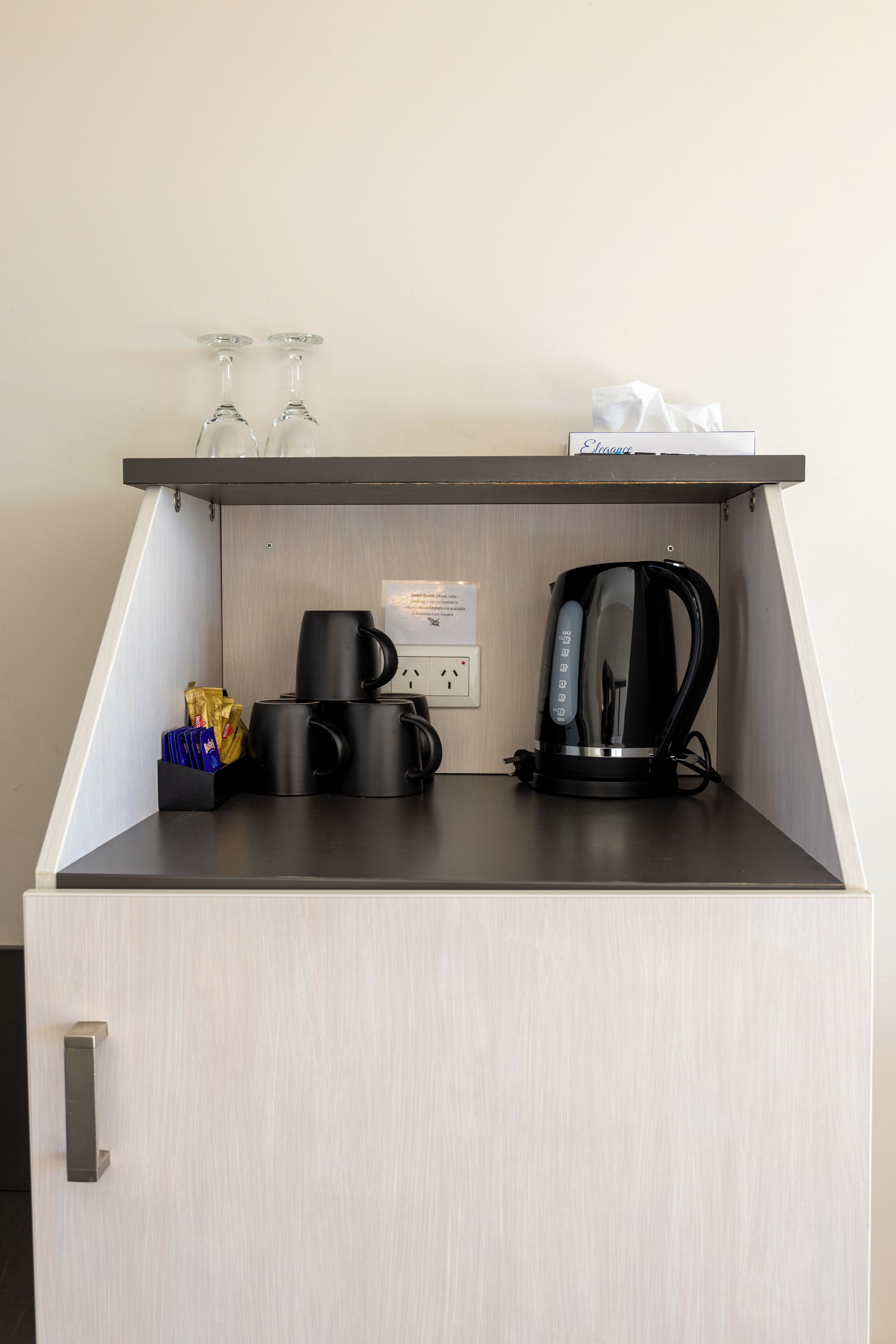 Une petite cuisine équipée d’une machine à café, de deux tasses et d’une boîte de mouchoirs.