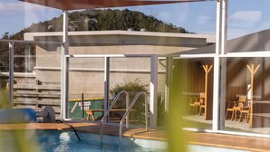 A swimming pool with a ladder, surrounded by a deck with chairs and a building in the background. - Beachfront At Bicheno (Bicheno)