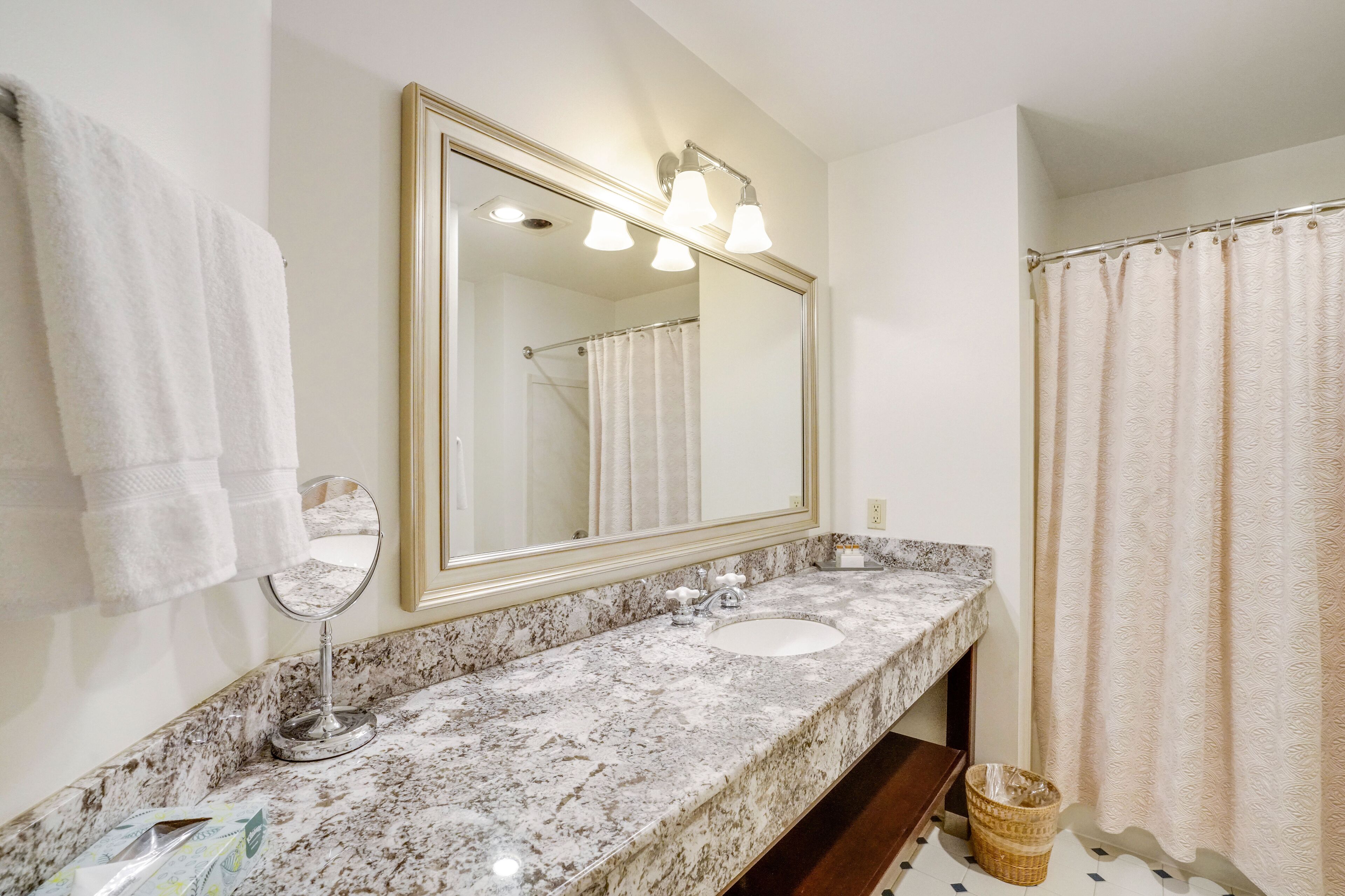 A bathroom with a marble sink, a large mirror, and a shower curtain.