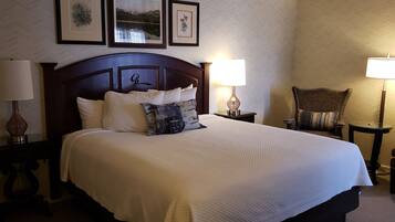 A hotel room with a large bed, two bedside tables with lamps, a chair, and framed pictures on the wall.