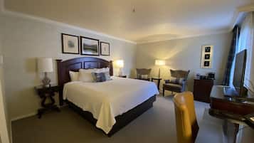 A hotel room with a large bed, bedside tables with lamps, a desk with a chair, and a television.