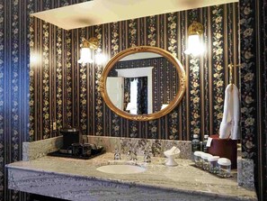 A bathroom with a large mirror, a sink, and a towel rack.