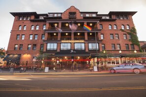 A historic hotel with a prominent entrance, multiple balconies, and flags.